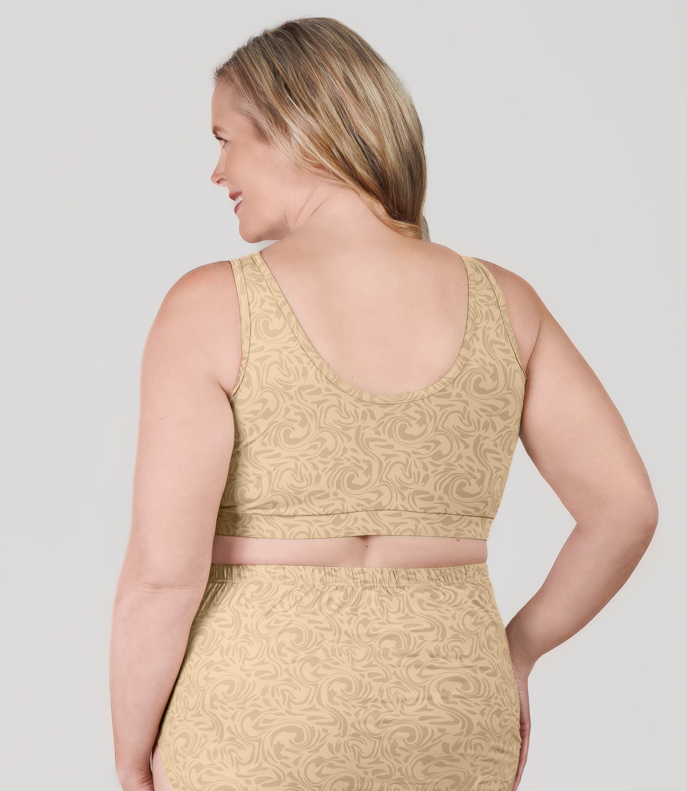 Plus size woman, facing back, wearing JunoActive's Junowear Hush Plus V-neck plus size Bra in ecru swirl print.