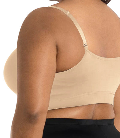 Close up of plus size model wearing JunoActive's Junowear Hush adjustable bralette in color ecru. Models hands are by her side and she's facing back.