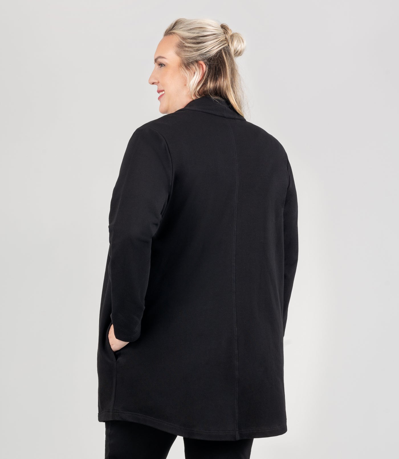 Model is facing back, wearing JunoActive's Mavie Cotton Long Wrap Jacket in color black. 