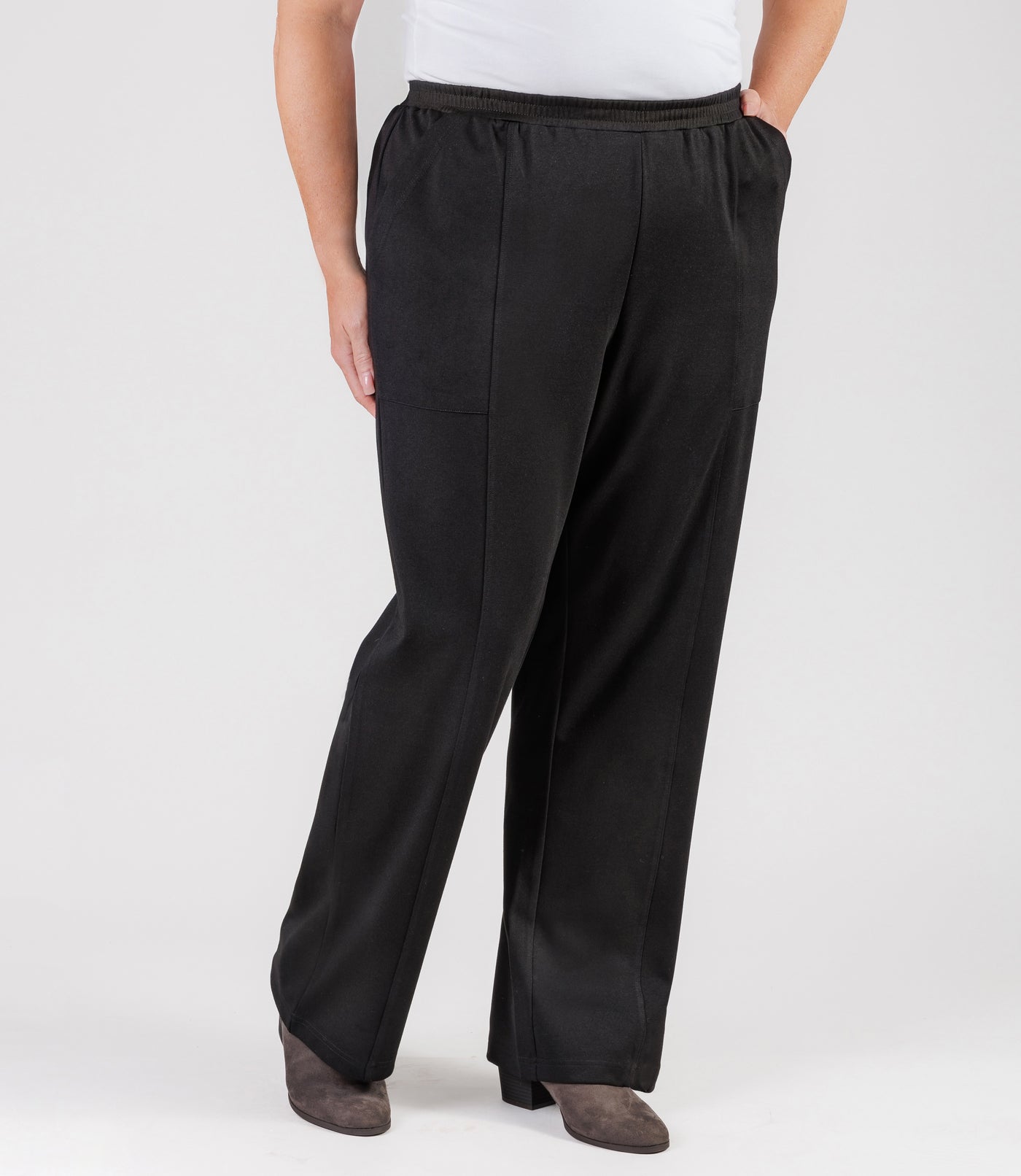 Plus size woman, facing front with one leg bent, wearing JunoActive's Ponte Center Seam Pocketed Pant in color black. 