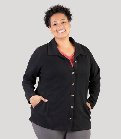 Plus size model, facing front, wearing JunoActive's JunoWaffle Cotton Long Sleeve Button top with her hands in her pockets of top. Top color is black.