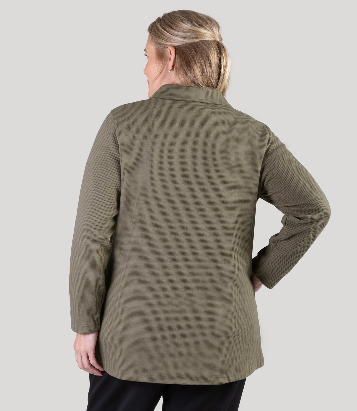 Plus size model, facing back, wearing JunoActive's JunoWaffle Cotton Long Sleeve Button top with her right hand on right hip and left hand by her left side.