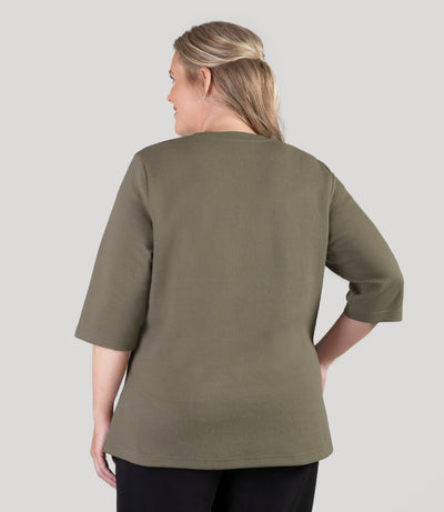 Plus size model, facing back, wearing JunoActive's JunoWaffle 3/4 Sleeve Button Top in color Olive.