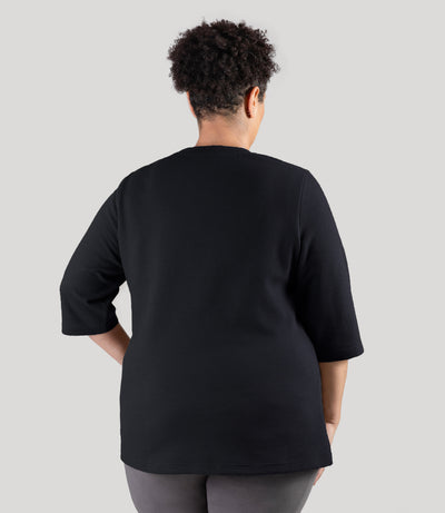 Plus size model, facing back, wearing JunoActive's JunoWaffle 3/4 Sleeve Button Top in color black.