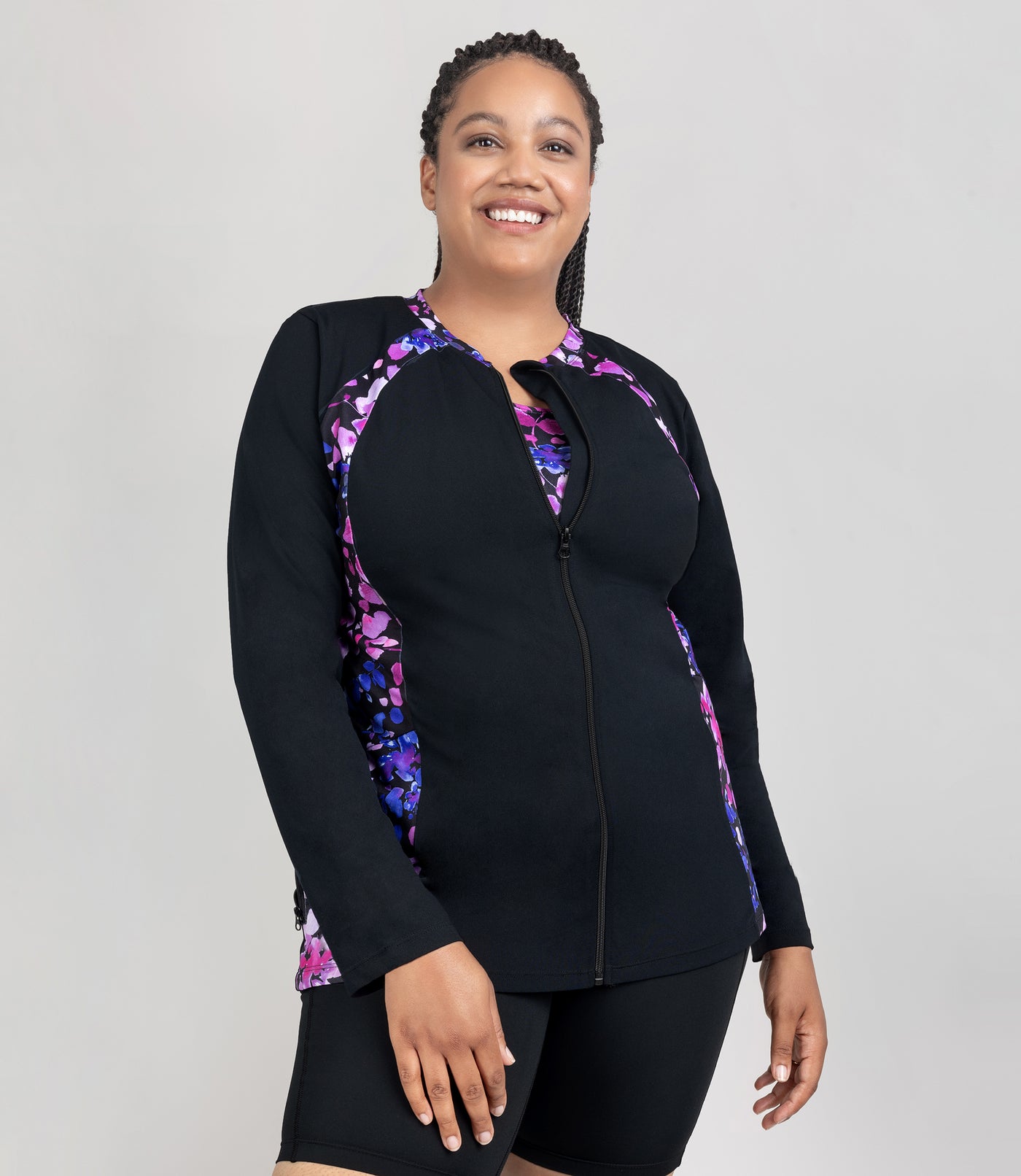 JunoActive model, facing front, wearing Aquasport Long Sleeve Zip Front Swim Jacket in solid black with  blue and pink floral elegance print accents.