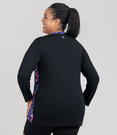 JunoActive model, facing back, wearing Aquasport Long Sleeve Zip Front Swim Jacket in solid black and blue and pink floral elegance print accents.