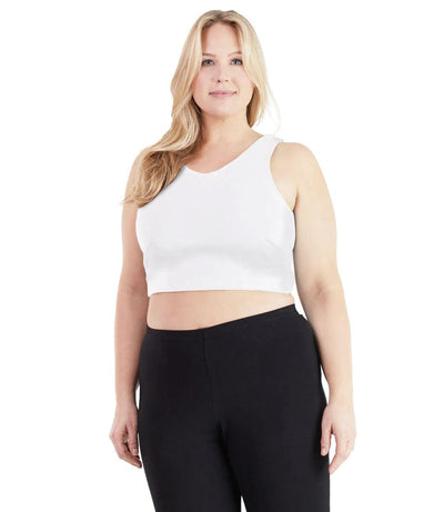 Plus size woman, facing front, wearing JunoActive plus size UltraKnit V-Neck Bras in White. The woman is wearing a pair of Black JunoActive leggings.