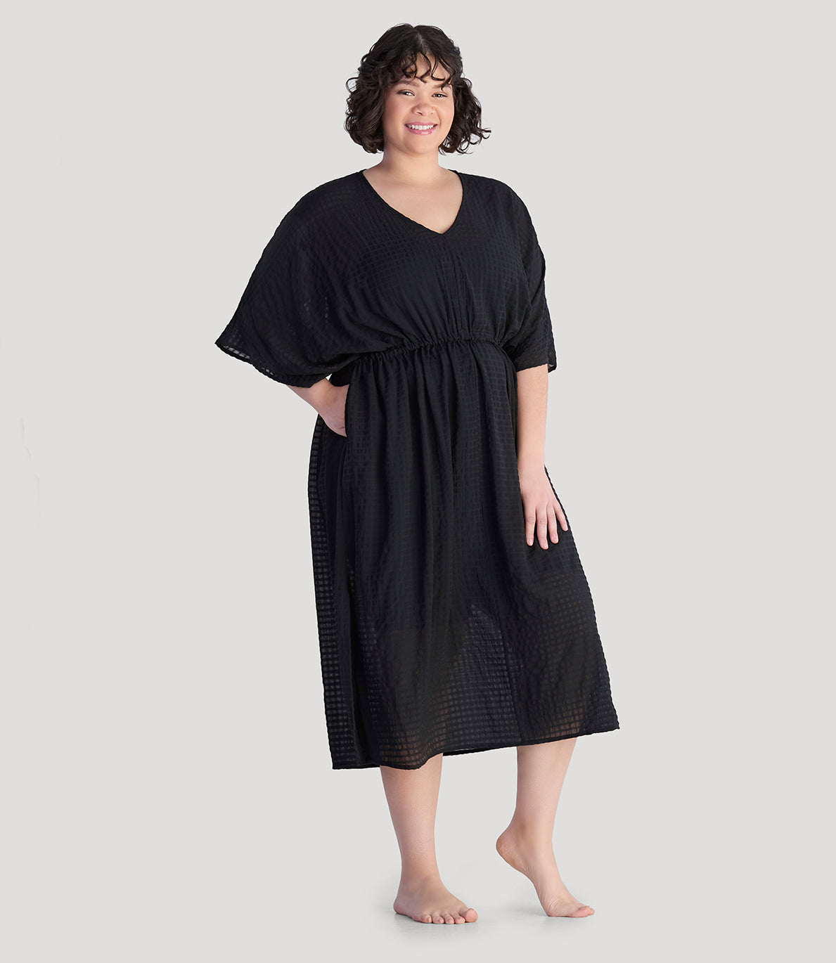 Plus size model, facing front, hand in pocket, wearing JunoActive's BellaStyle V-Neck Long Gathered Caftan in color black.