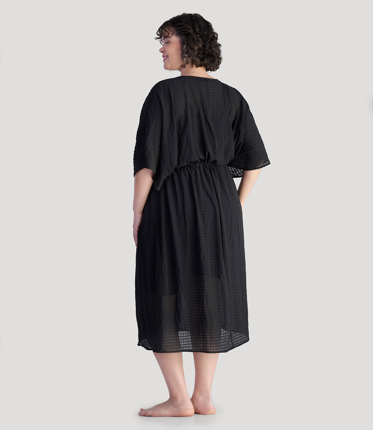 Plus size model, facing back, wearing JunoActive's BellaStyle V-Neck Long Gathered Caftan in color black.