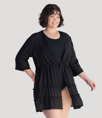 Plus size model, facing front, wearing JunoActive's BellaStyle Tie Front Tiered Cover-Up in color black.