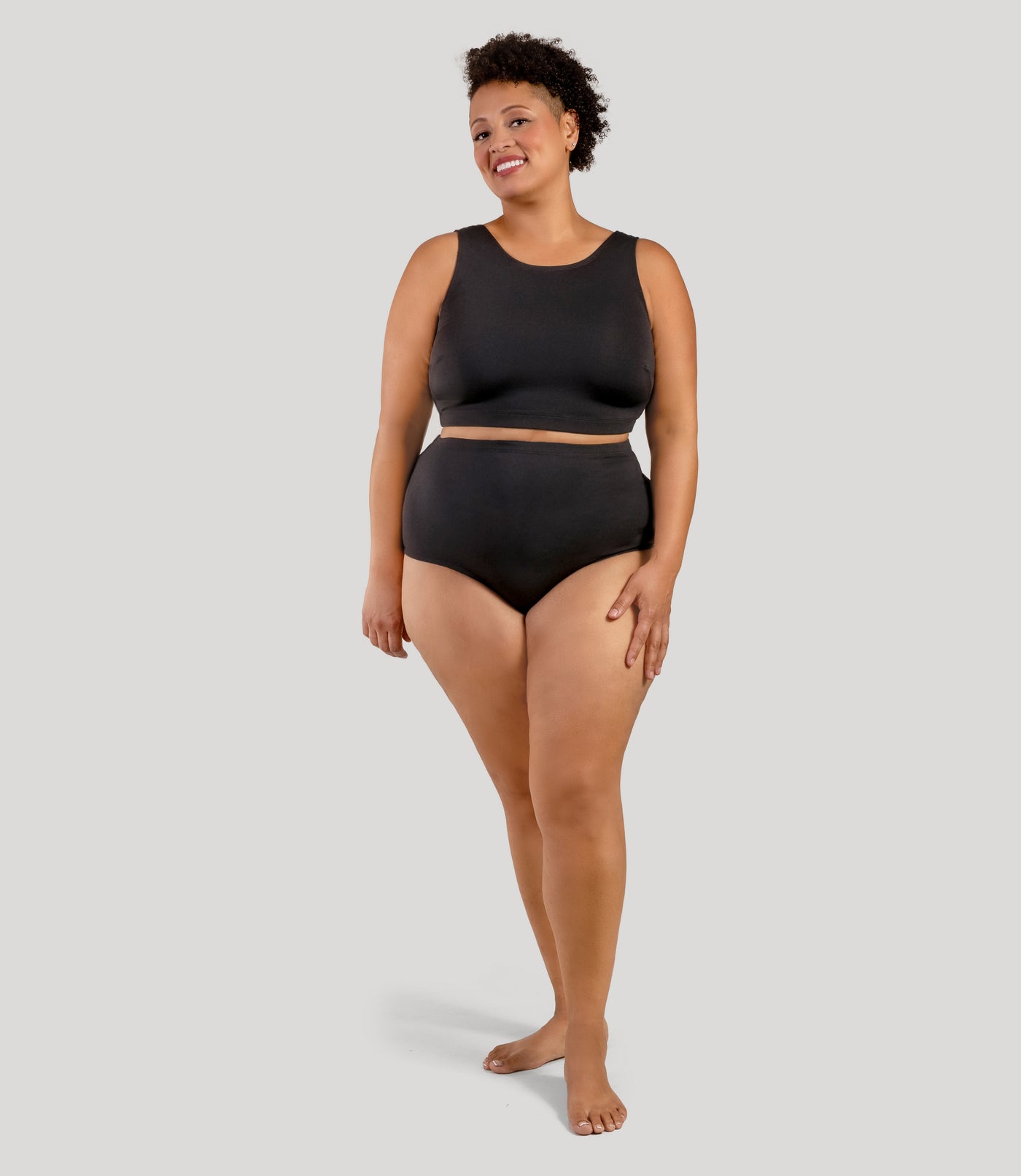 Plus size person, facing front, wearing JunoActive's QuikWik Full Fit plus size underwear in color black on a gray background.