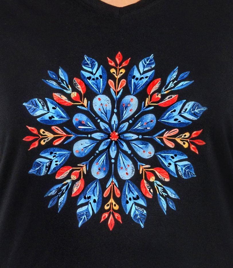 Close up of plus size Woman, facing front, wearing a JunoActive black plus size  long sleeve shirt with colorful scandi inspired snowflake design.