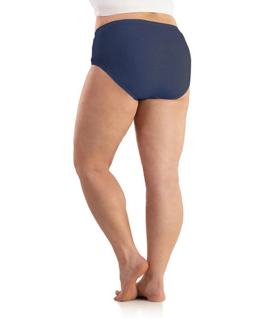 Bottom half of plus sized woman, back view, wearing JunoActive SupraKnit Briefs in navy. This brief fits to the waistline with a conservative leg opening.