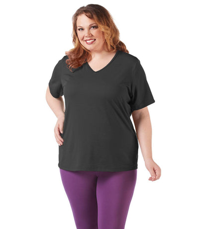 Plus size woman, facing front, wearing JunoActive plus size SoftWik V-Neck Tee in the color Black. She is wearing JunoActive Plus Size Leggings in the color Grape. 