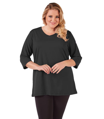 Plus size woman, facing front, wearing JunoActive plus size SoftWik V-Neck Tunic with ¾ sleeves in the color Black. She is wearing JunoActive Plus Size Leggings in the color Black.