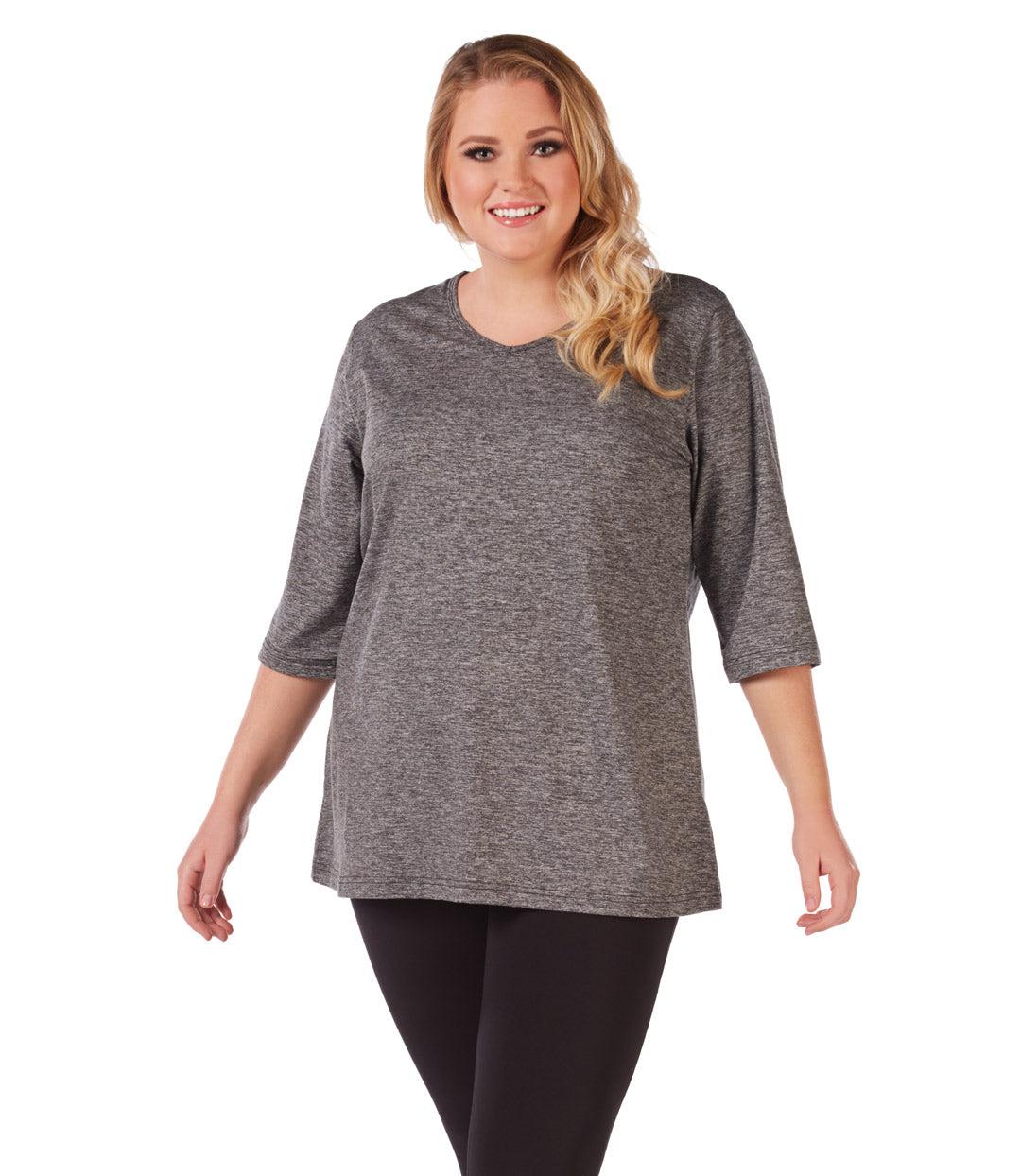 Plus size woman, facing front, wearing JunoActive plus size SoftWik V-Neck Tunic with ¾ sleeves in the color Heather Grey. She is wearing JunoActive Plus Size Leggings in the color Black.