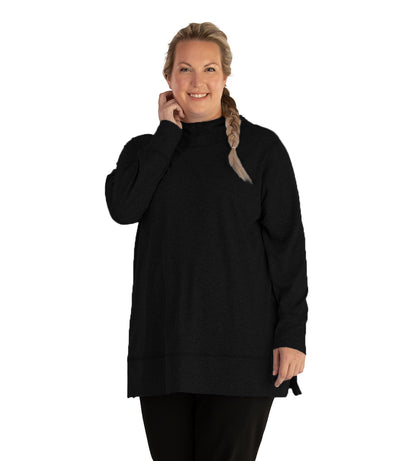 Plus size woman, facing front, wearing JunoActive plus size SoftWik Long Sleeve Hoodie in the color Black. She is wearing JunoActive Plus Size Leggings in the color Black.