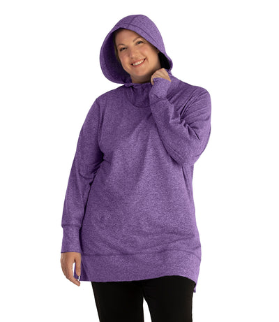 Plus size woman, facing front, wearing JunoActive plus size SoftWik Long Sleeve Hoodie in the color Heather Amethyst. She has the hood up on her head, covering her hair. She is wearing JunoActive Plus Size Leggings in the color Black.