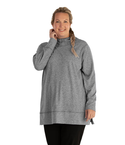 Plus size woman, facing front, wearing JunoActive plus size SoftWik Long Sleeve Hoodie in the color Heather Grey. She is wearing JunoActive Plus Size Leggings in the color Black.