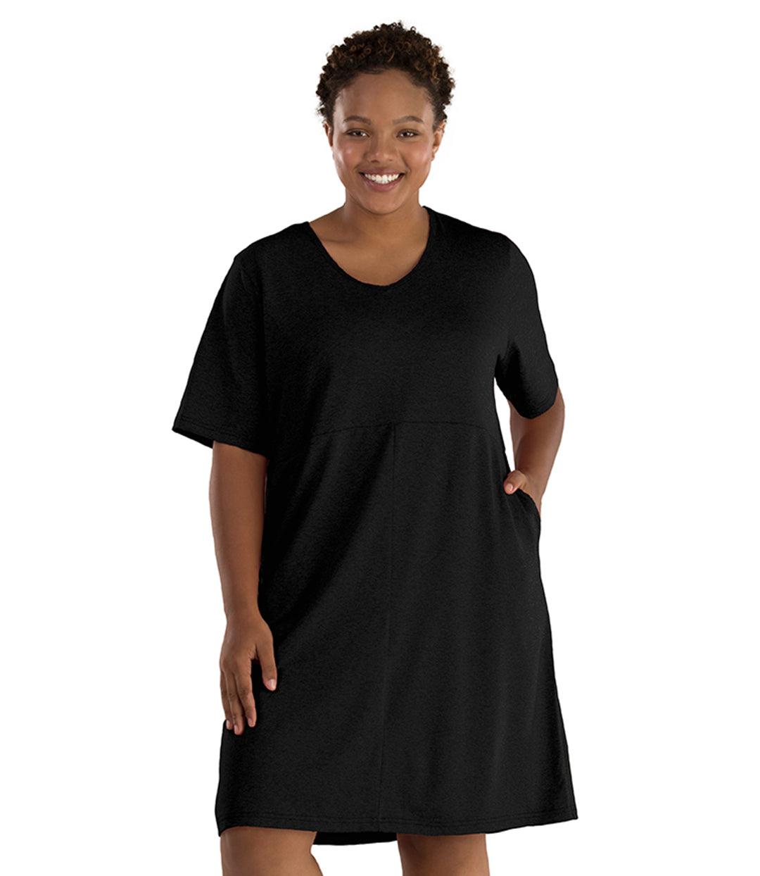 Plus size woman, facing front, wearing JunoActive SoftWik short sleeve dress with pockets. Sleeves are longer and just before elbow. Hemline is above knees. The color is black. 