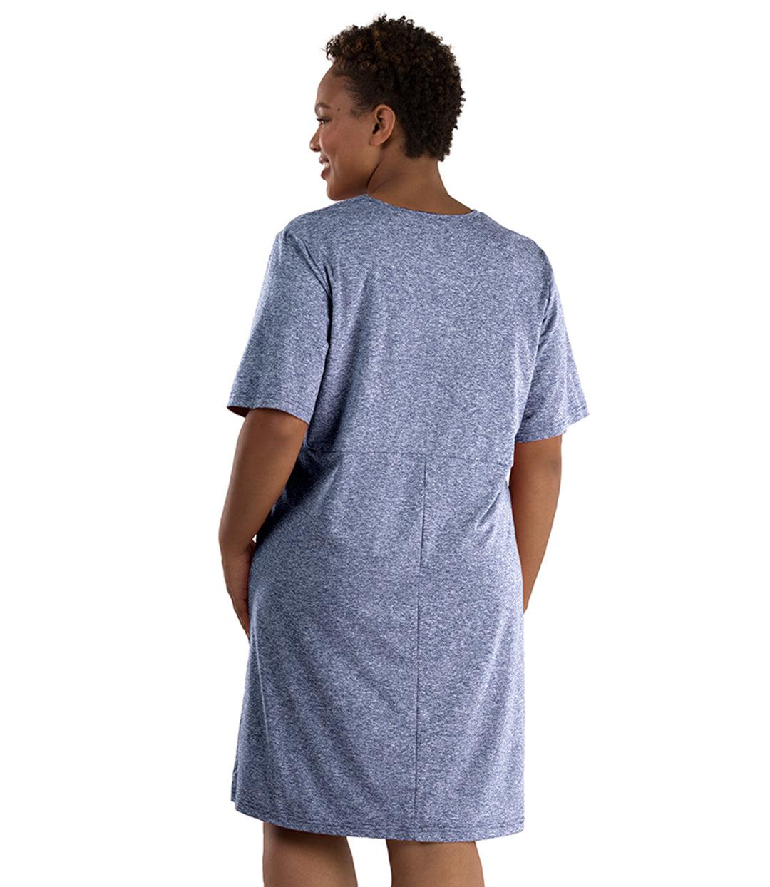 Plus size woman, facing back, left arm on hip, right arm down by side. She's wearing JunoActive SoftWik short sleeve dress with pockets. Sleeves are longer and just before elbow. Hemline is above knees. The color is heather navy. 
