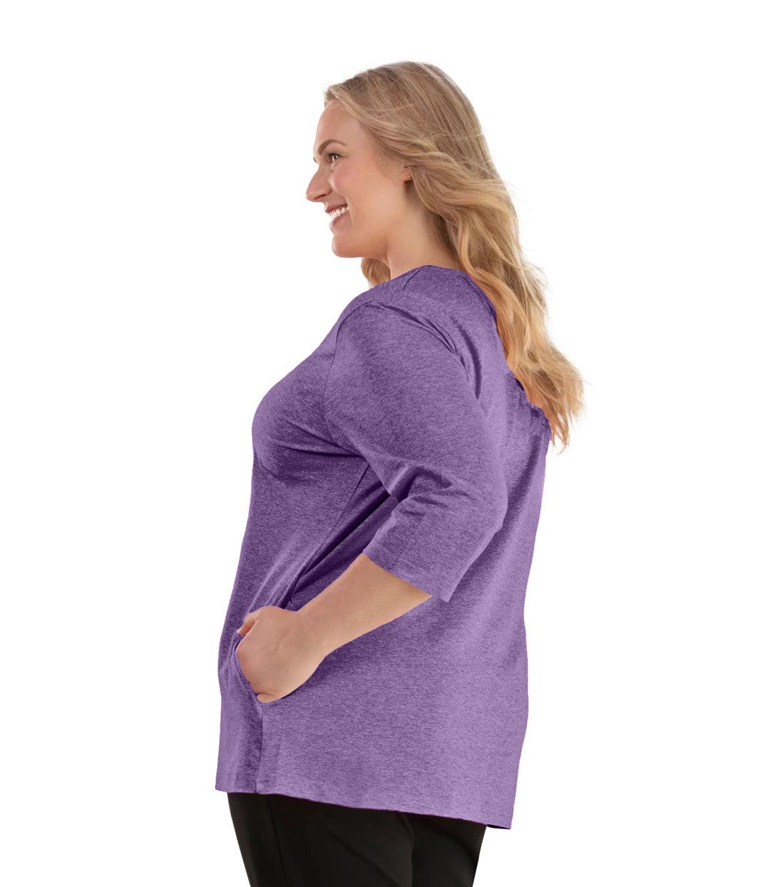 Plus size woman, facing left, wearing JunoActive plus size SoftWik V-Neck ¾ Sleeve Top with Pockets in the color Heather Amethyst. She is wearing JunoActive Plus Size Leggings in the color Black.