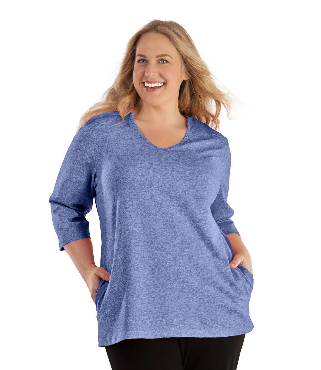 Plus size woman, facing front, wearing JunoActive plus size SoftWik V-Neck ¾ Sleeve Top with Pockets in the color Heather Royal. She is wearing JunoActive Plus Size Leggings in the color Black.