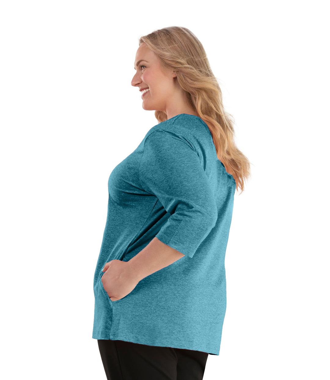 Plus size woman, facing left, wearing JunoActive plus size SoftWik V-Neck ¾ Sleeve Top with Pockets in the color Ocean Blue. She is wearing JunoActive Plus Size Leggings in the color Black.