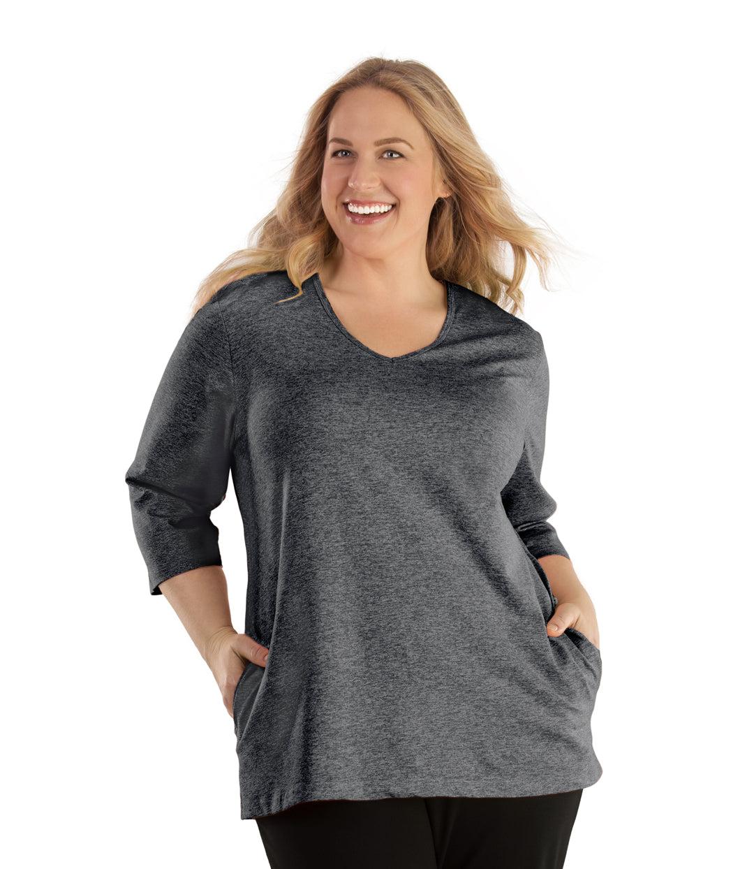 Plus size woman, facing front, wearing JunoActive plus size SoftWik V-Neck ¾ Sleeve Top with Pockets in the color Heather Grey. She is wearing JunoActive Plus Size Leggings in the color Black.