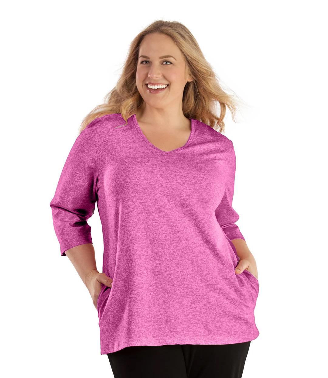 Plus size woman, facing front, wearing JunoActive plus size SoftWik V-Neck ¾ Sleeve Top with Pockets in the color Heather Fuschia. She is wearing JunoActive Plus Size Leggings in the color Black.