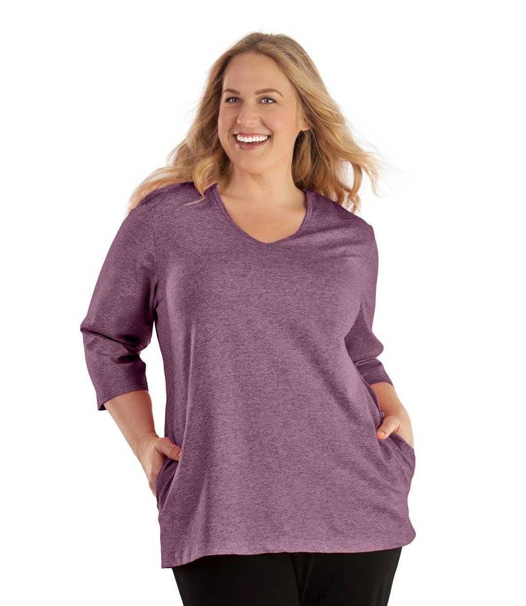 Plus size woman, facing front, wearing JunoActive plus size SoftWik V-Neck ¾ Sleeve Top with Pockets in the color Heather Merlot. She is wearing JunoActive Plus Size Leggings in the color Black.