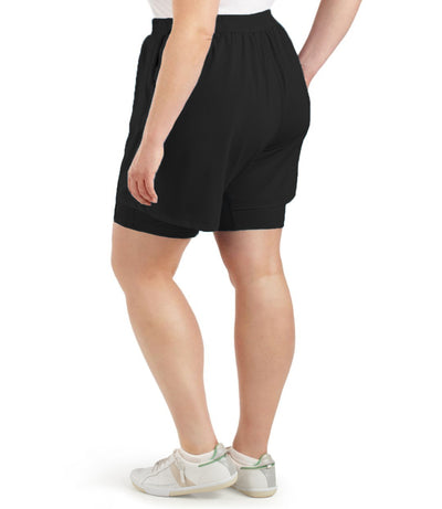 Back view of bottom half of plus sized model wearing JunoActives QuikWik Lite Dual Layer Short in black. There are two layers with the bottom being a tight bike short and the outer layer a looser material.