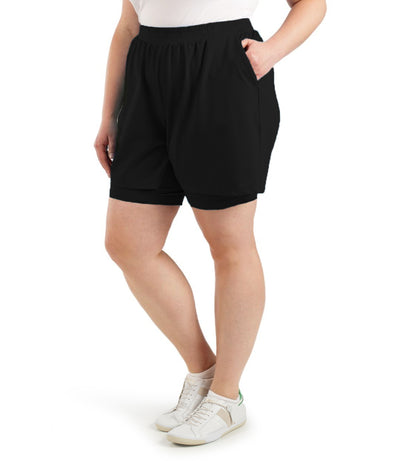 Front view of bottom half of plus sized model wearing JunoActives QuikWik Lite Dual Layer Short in black. There are two layers with the bottom being a tight bike short and the outer layer a looser material.