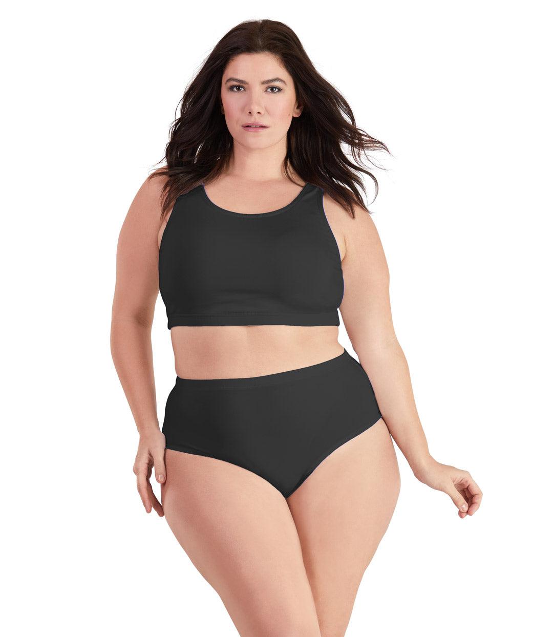 Plus size woman, facing front, wearing JunoActive plus size QuikWik Soft Control Bra Top in Black. The woman is wearing a pair of coordinating QuikWik Comfort plus size Briefs in Black. 