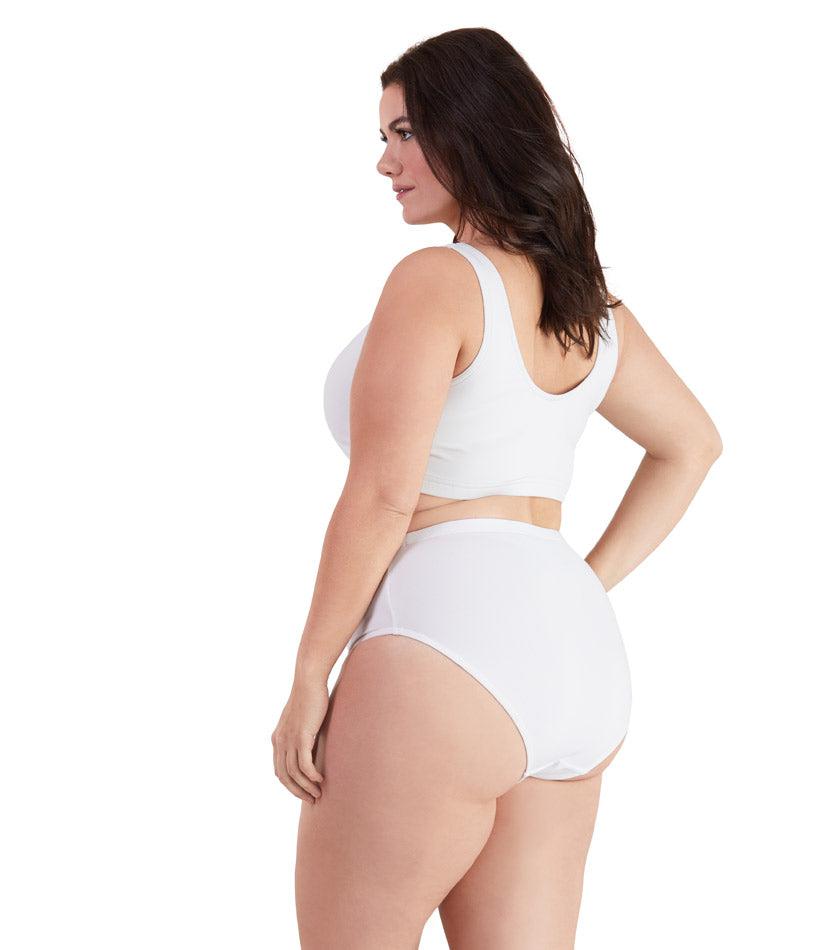 Plus size woman, facing back left, wearing JunoActive plus size QuikWik Soft Control Bra Top in White. The woman is wearing a pair of coordinating QuikWik Comfort plus size Briefs in White.