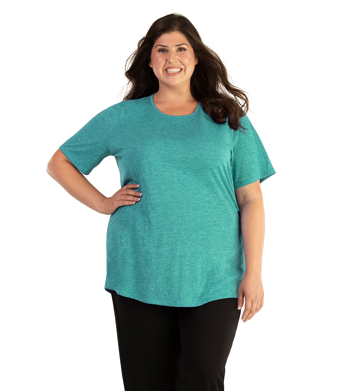 Plus size woman, facing front, wearing JunoActive plus size QuikLite Scoop Neck Short Sleeve top in the color Fern Green. She is wearing JunoActive Plus Size Leggings in the color black. 