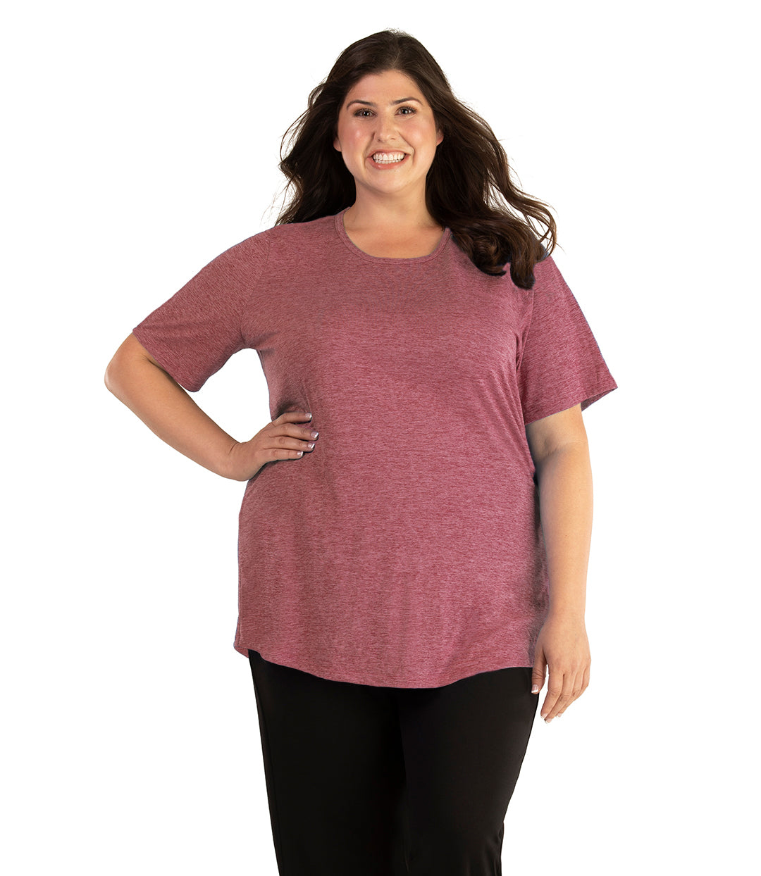 Plus size woman, facing front, wearing JunoActive plus size QuikLite Scoop Neck Short Sleeve top in the color Roseate. She is wearing JunoActive Plus Size Leggings in the color black.