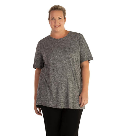 Plus size woman, facing front, wearing JunoActive plus size QuikLite Scoop Neck Short Sleeve top in the color Heather Charcoal. She is wearing JunoActive Plus Size Leggings in the color black. 