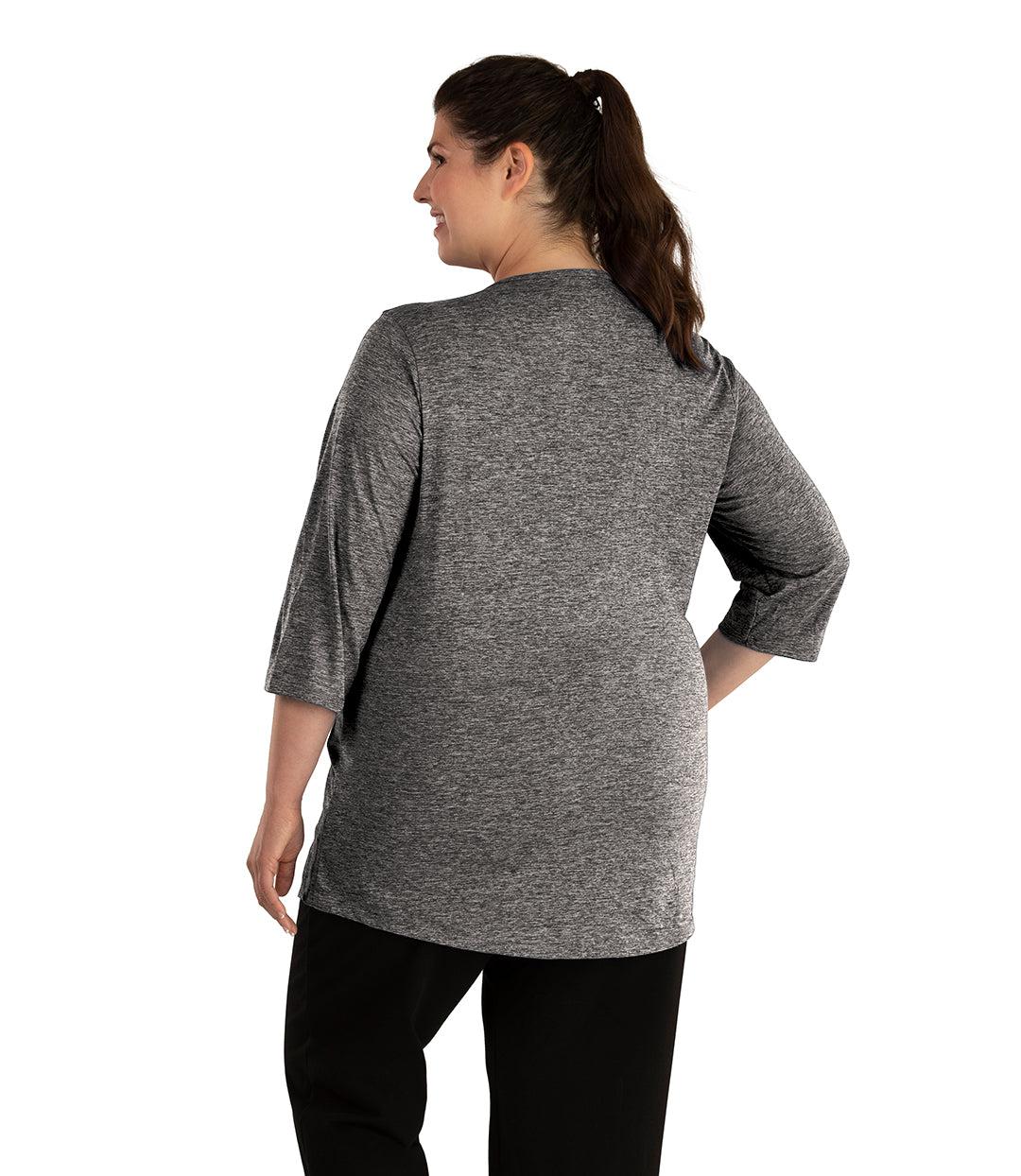 Plus size woman, facing back looking left, wearing JunoActive plus size QuikLite Scoop Neck ¾ Sleeve Top in the color Heather Charcoal. She is wearing JunoActive Plus Size Leggings in the color Black.