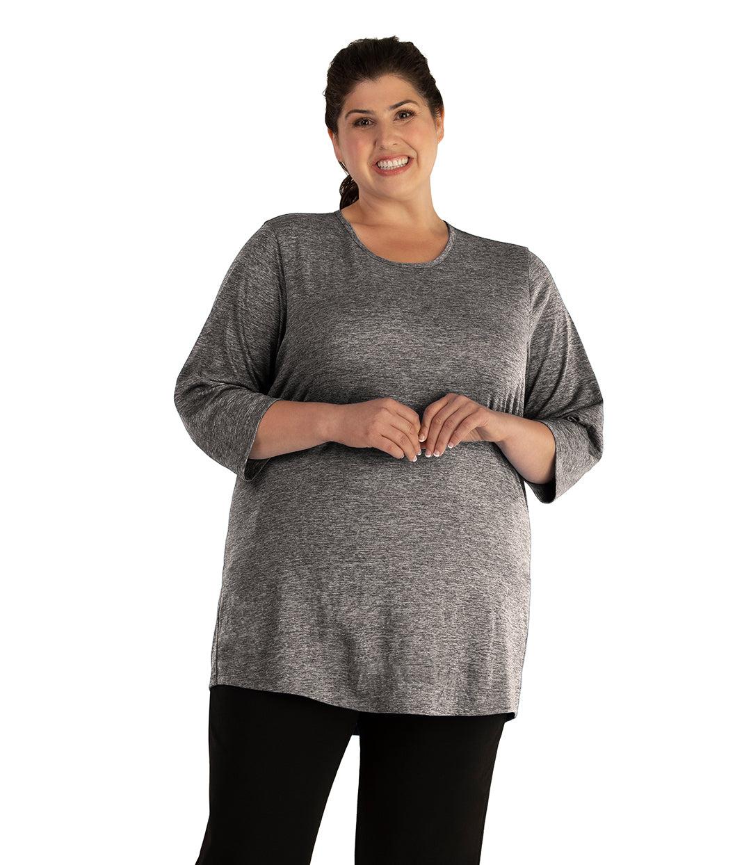 Plus size woman, facing front, wearing JunoActive plus size QuikLite Scoop Neck ¾ Sleeve Top in the color Heather Charcoal. She is wearing JunoActive Plus Size Leggings in the color Black.