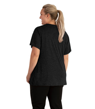 Plus size woman, facing back looking to the left, wearing JunoActive plus size QuikLite V-Neck Short Sleeve top in the color Heather Black. She is wearing JunoActive Plus Size Leggings in the color black. 