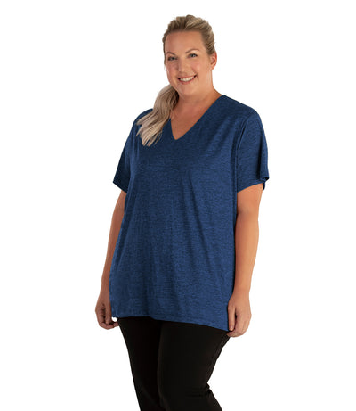 Plus size woman, facing front, wearing JunoActive plus size QuikLite V-Neck Short Sleeve top in the color Heather Blue. She is wearing JunoActive Plus Size Leggings in the color black. 