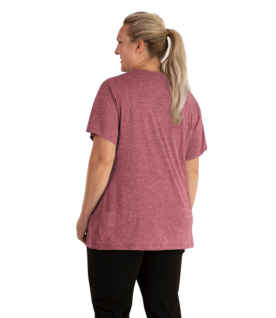 Plus size woman, facing back looking to the left, wearing JunoActive plus size QuikLite V-Neck Short Sleeve top in the color Roseate. She is wearing JunoActive Plus Size Leggings in the color black. 