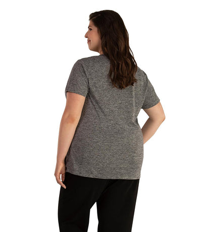 Plus size woman, facing back looking to the left, wearing JunoActive plus size QuikLite V-Neck Short Sleeve top in the color Heather Charcoal. She is wearing JunoActive Plus Size Leggings in the color black. 