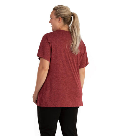 Plus size woman, facing back looking to the left, wearing JunoActive plus size QuikLite V-Neck Short Sleeve top in the color Heather Garnet Red. She is wearing JunoActive Plus Size Leggings in the color black. 