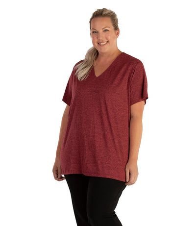 Plus size woman, facing front, wearing JunoActive plus size QuikLite V-Neck Short Sleeve top in the color Heather Garnet Red. She is wearing JunoActive Plus Size Leggings in the color black. 
