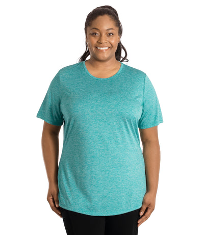Plus size woman wearing JunoActive's SunLite Scoop Neck front view wearing black pants and hands by side in heather coastal teal.
