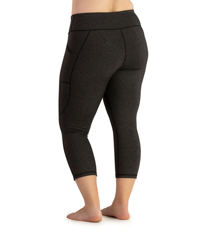 Bottom half of plus sized woman, facing back with pockets showing, wearing JunoActive JunoStretch Side Pocket Capris in heather charcoal. The hem falls a few inches above ankle and have pockets on both sides. 
