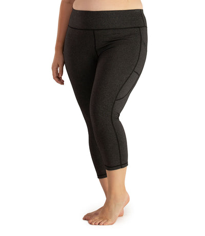 Bottom half of plus sized woman, facing front with pockets showing, wearing JunoActive JunoStretch Side Pocket Capris in heather charcoal. The hem falls a few inches above ankle and have pockets on both sides. 
