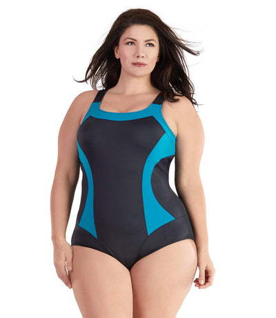 Plus size woman, facing front, wearing JunoActive plus size QuikEnergy Color Block Tank Suit Black and Turq. The blocking at the neckline and princess panels is turquoise. Side panels, straps, center front, and leg blocking are black, has a scoop neckline and conservative leg opening.